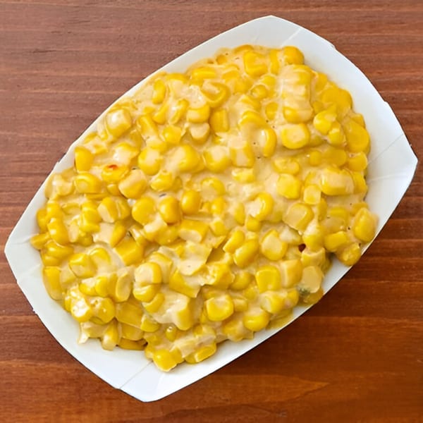 Creamed corn in a white paper tray, a classic side dish from Smokin' Jones BBQ.